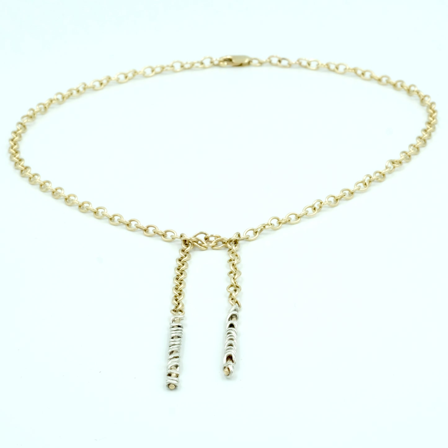 This flattering air loom solid gold Tie Necklace is made in London by Christina Elizabeth. The length of the necklace can adapt to go closer up to your neckline. Made of solid gold wire with an element of sterling silver wire twisted round the ends. Falls beautifully and feels substantially weighty. Can be made in any combination of precious metals.