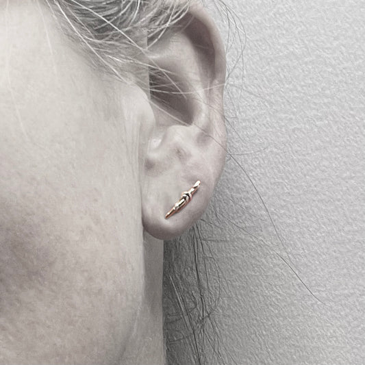 Shown on the Ear, The Golden Thread Longer Earring stud is randomly made so each piece is slightly different to the next and is made of recycled gold and silver. The earring posts are recycled gold. These are Hallmarked by the London Assay Office